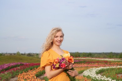 Photo of Happy woman with spring bouquet of flowers in beautiful tulip field