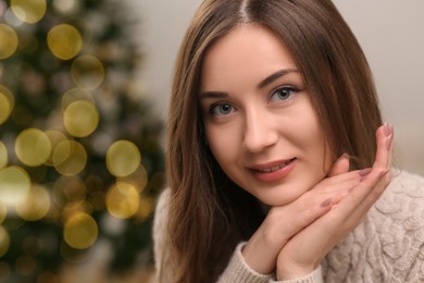 Photo of Beautiful young woman on blurred background, closeup and space for text. Celebrating Christmas