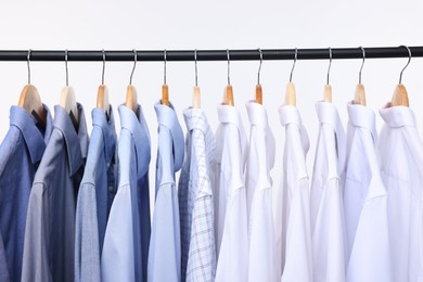 Dry-cleaning service. Many different clothes hanging on rack against white background, closeup