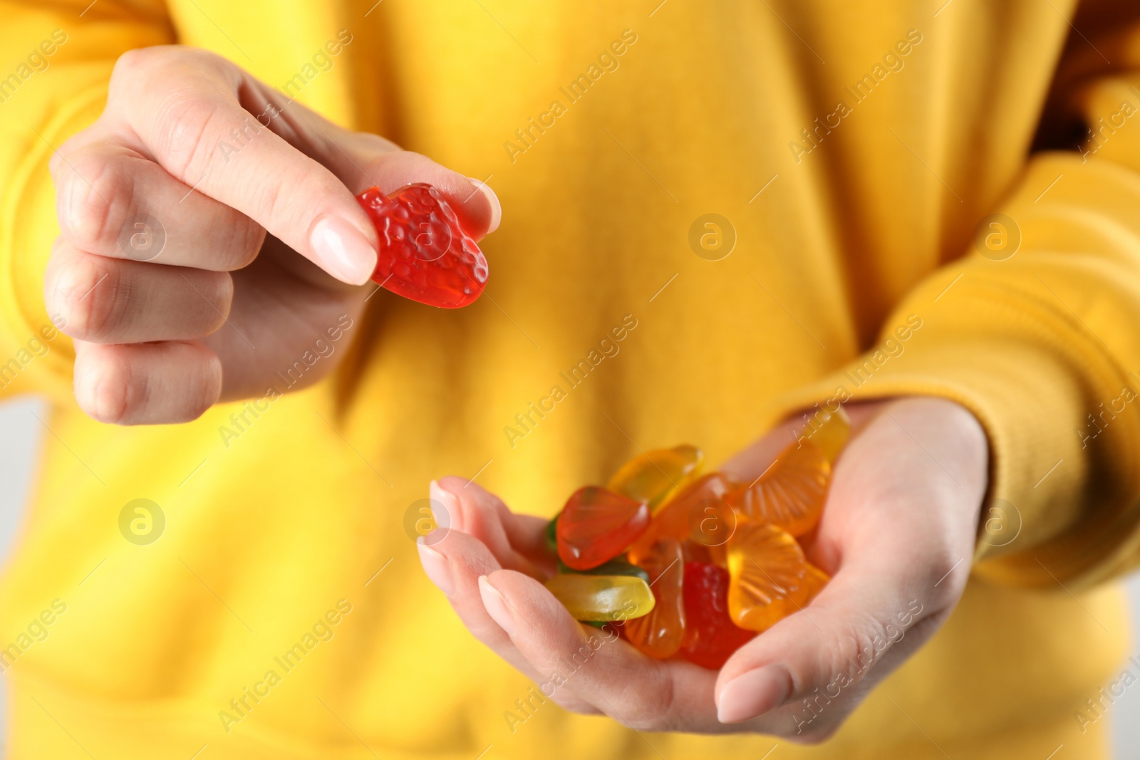 Photo of Woman holding handful with delicious gummy fruit shaped candies, closeup