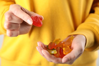 Photo of Woman holding handful with delicious gummy fruit shaped candies, closeup