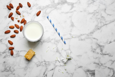 Photo of Glass with milk, nuts and honeycomb on light background, flat lay