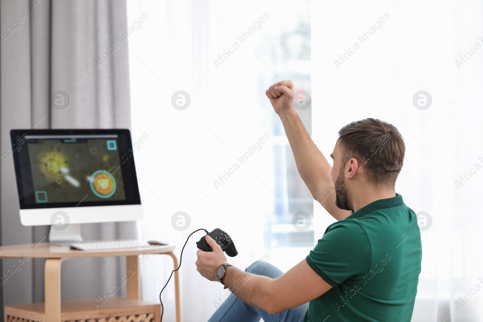 Photo of Young man playing video game at home