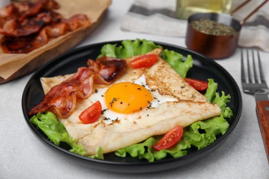 Delicious crepe with egg served on light gray table, closeup. Breton galette