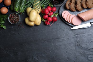 Photo of Flat lay composition with kvass and other okroshka ingredients on black table, space for text. Traditional Russian summer soup