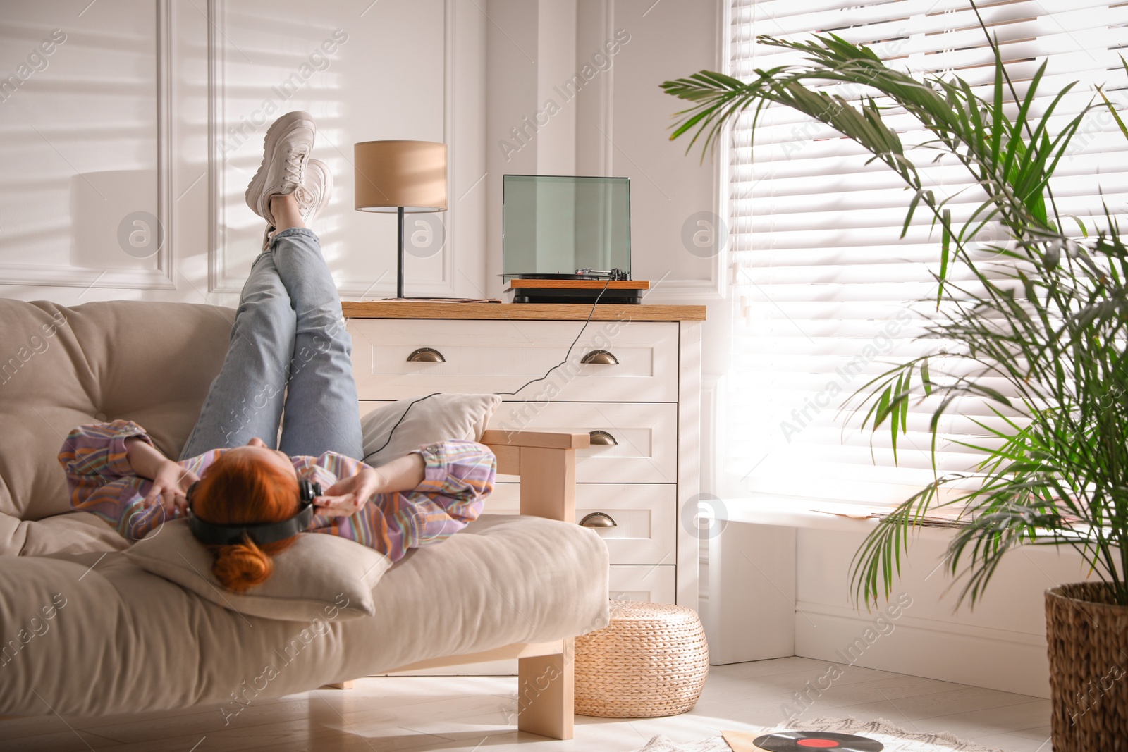 Photo of Young woman listening to music with turntable in living room