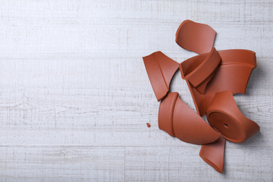 Photo of Broken terracotta flower pot on wooden background, flat lay. Space for text