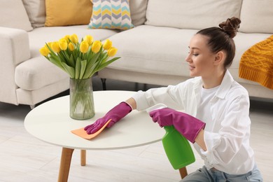 Photo of Spring cleaning. Young woman tidying up living room at home