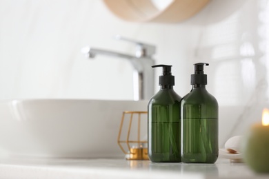 Green soap dispensers on countertop near sink in bathroom. Space for text