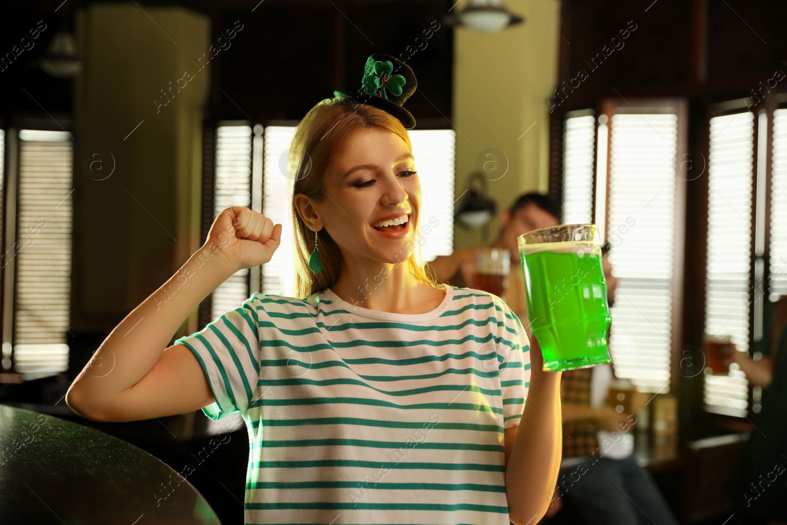 Photo of Young woman with glass of green beer in pub. St. Patrick's Day celebration