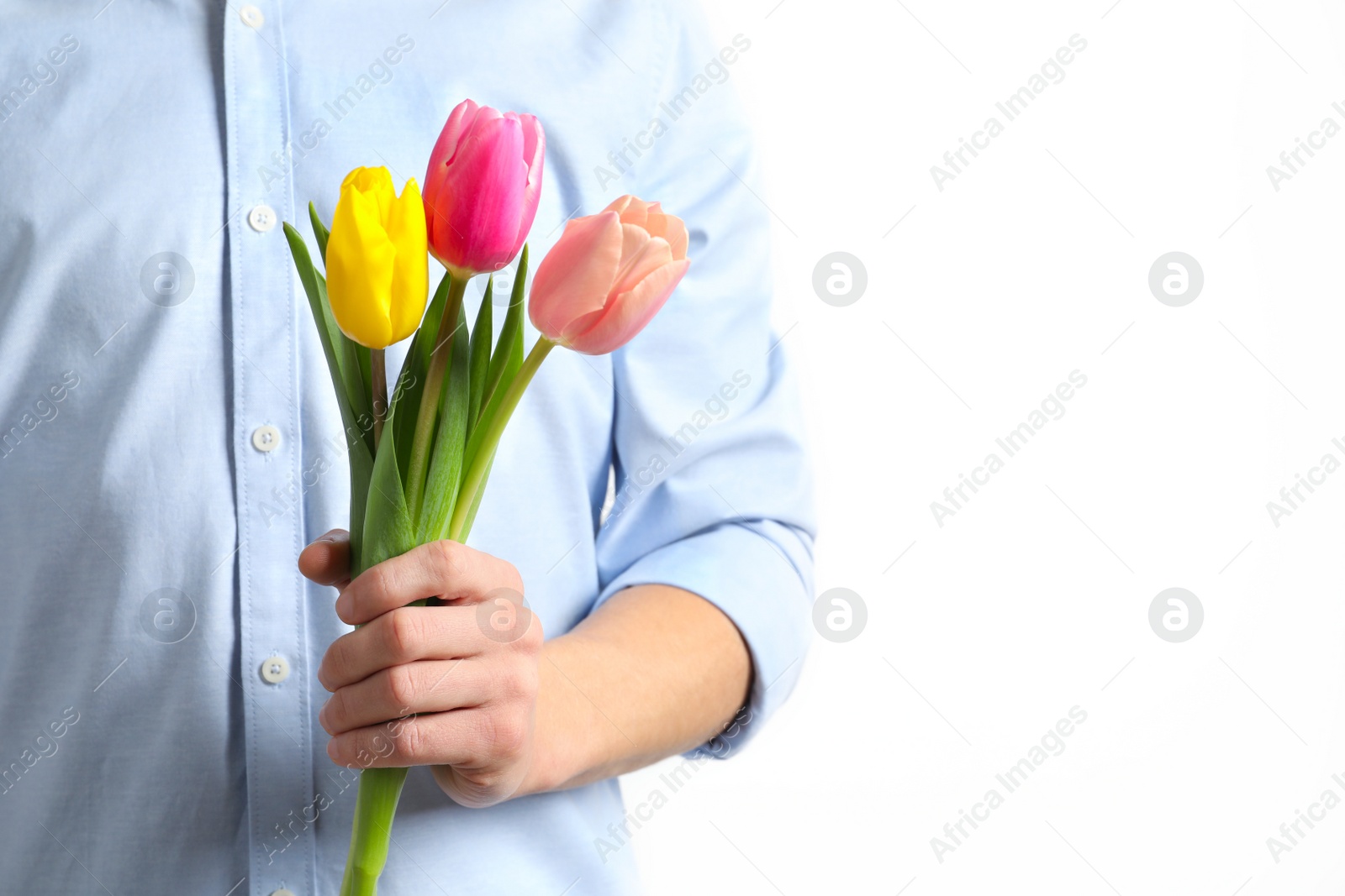 Photo of Man holding beautiful spring tulips on light background, closeup. International Women's Day