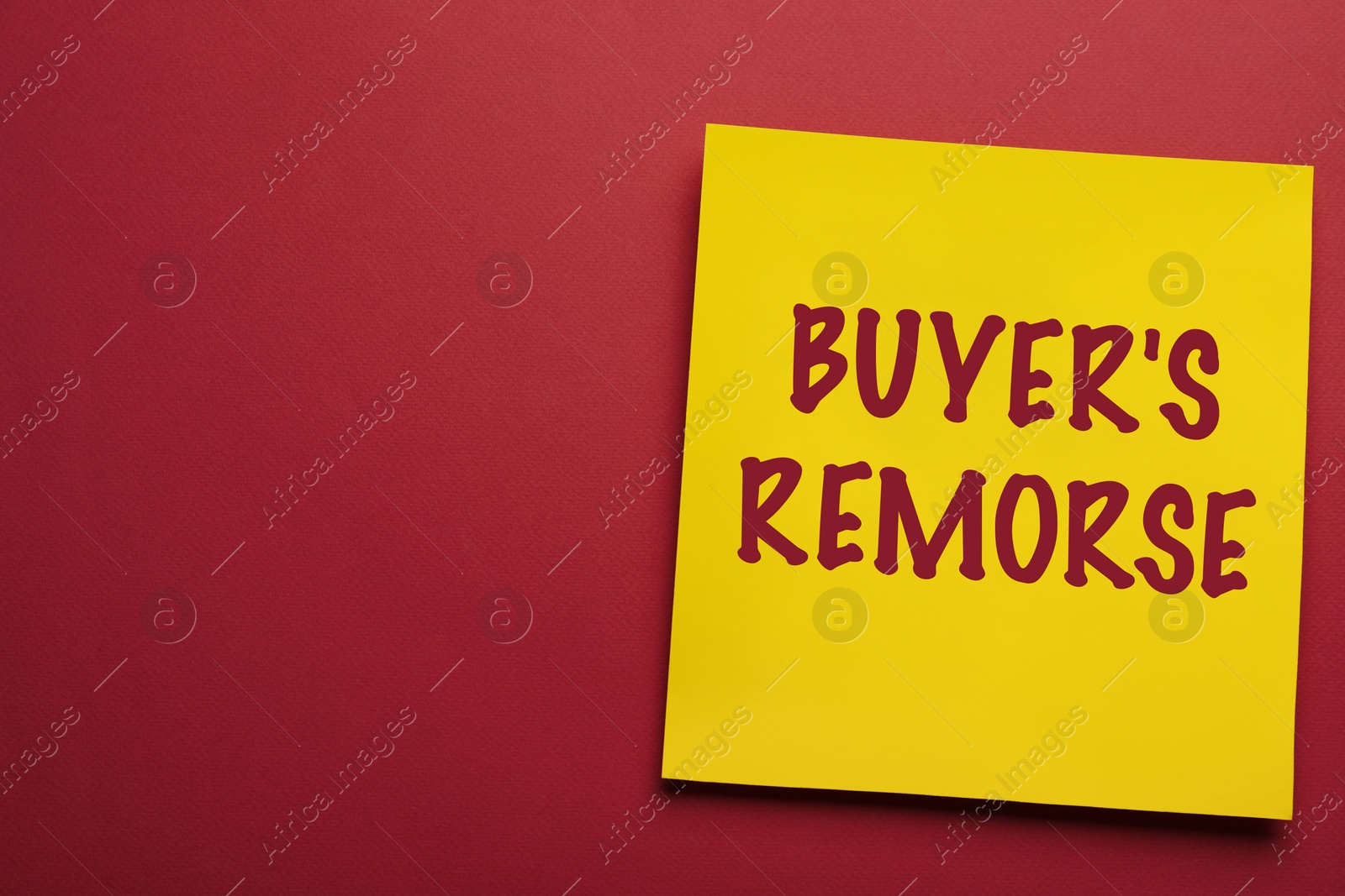 Image of Yellow card with text Buyer's Remorse on dark red background, top view. Space for text