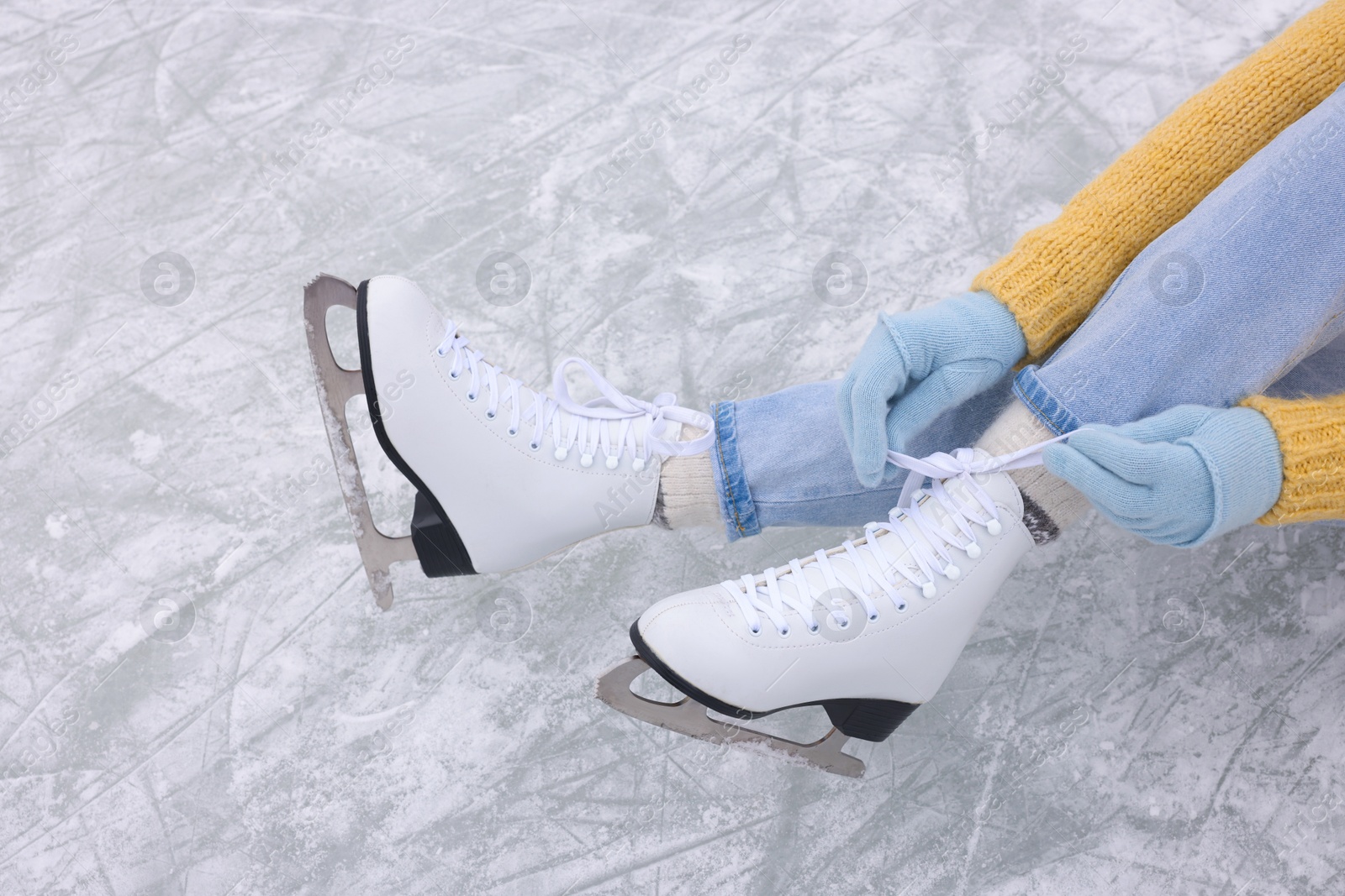 Photo of Woman lacing figure skates on ice, above view
