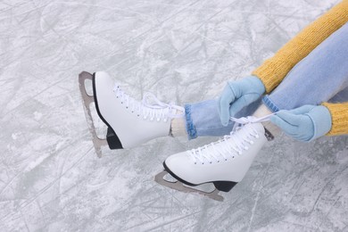 Photo of Woman lacing figure skates on ice, above view