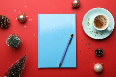 Photo of Light blue planner, cup of coffee and Christmas decor on red background, flat lay