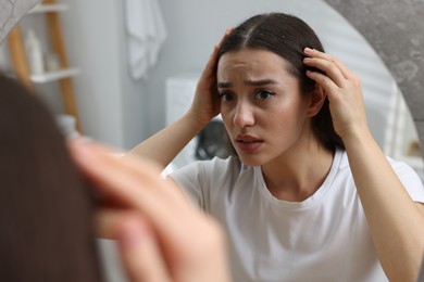 Photo of Emotional woman examining her hair and scalp at home. Dandruff problem
