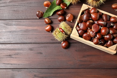 Fresh sweet edible chestnuts on wooden table, flat lay. Space for text