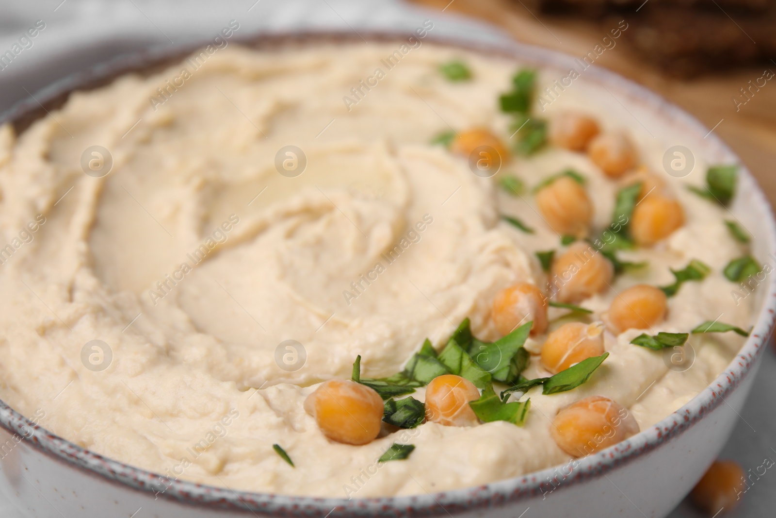 Photo of Bowl of delicious hummus with chickpeas, closeup