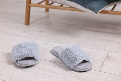 Photo of Grey soft slippers on light wooden floor indoors, closeup