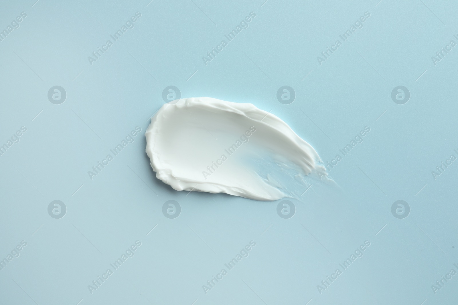 Photo of Sample of hand cream on light blue background, top view