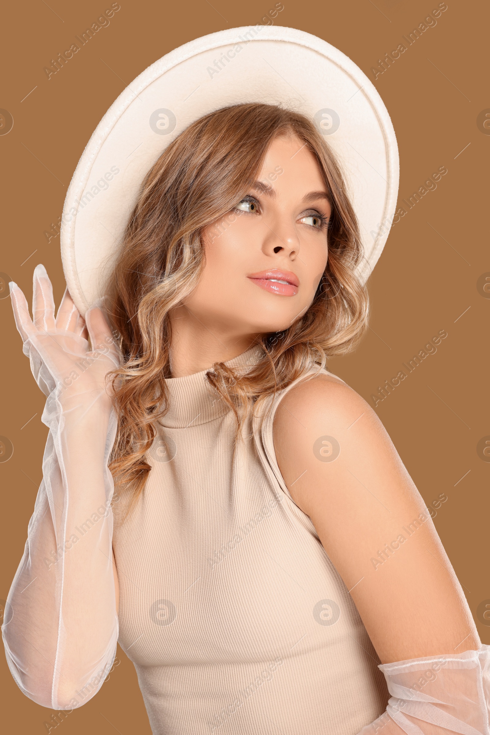 Photo of Portrait of beautiful young woman in stylish hat on light brown background