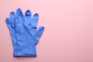 Pair of medical gloves on pink background, flat lay. Space for text