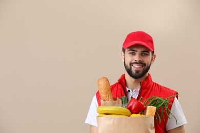 Photo of Man holding paper bag with fresh products on color background, space for text. Food delivery service