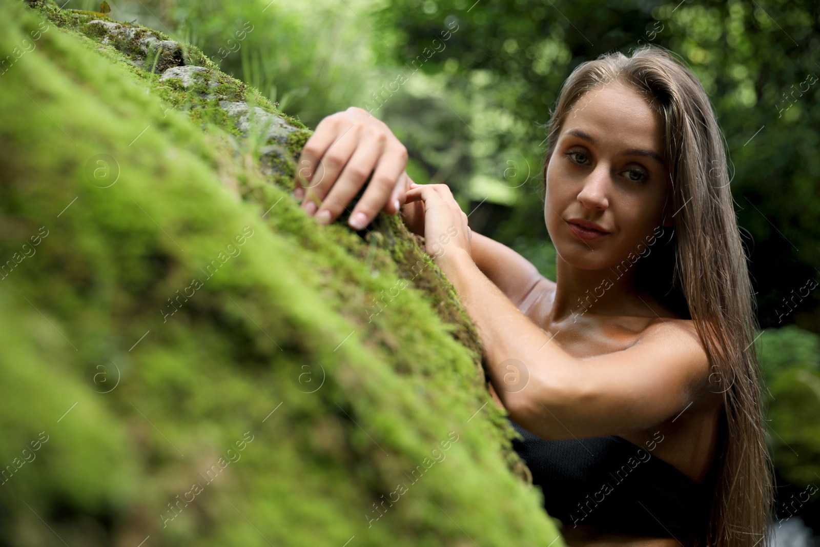 Photo of Beautiful young woman in stylish bikini near rock outdoors