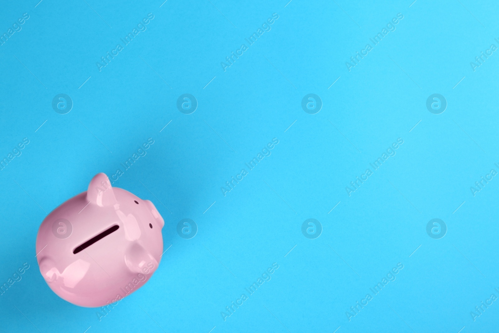 Photo of Pink piggy bank on blue background, top view. Space for text