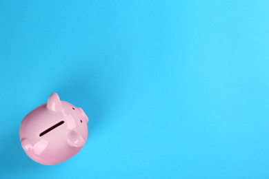 Photo of Pink piggy bank on blue background, top view. Space for text