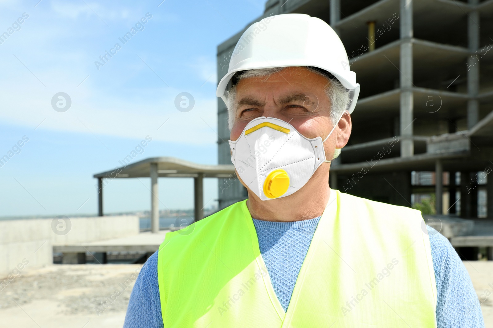 Photo of Professional builder in safety equipment at construction site, space for text