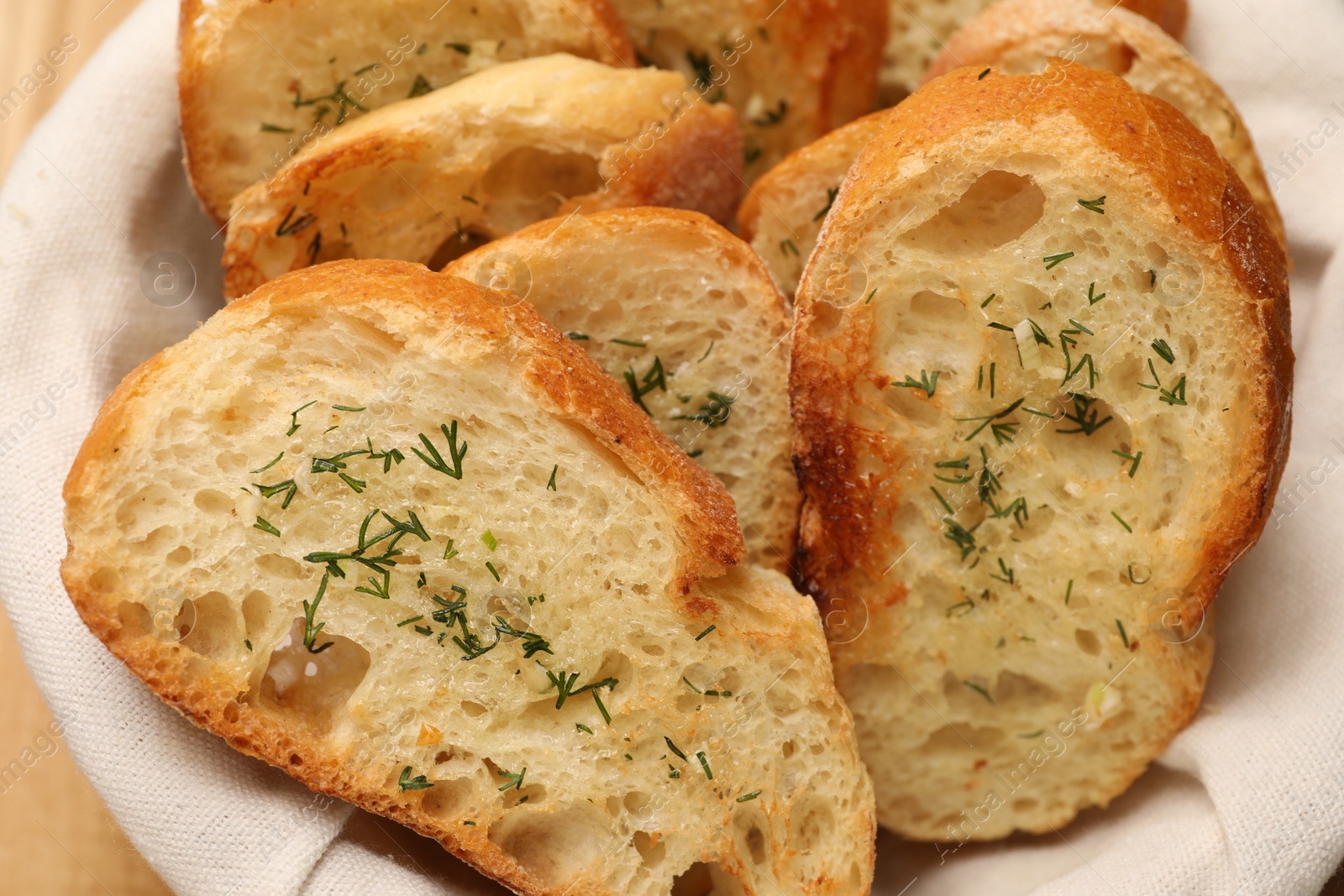 Photo of Tasty baguette with garlic and dill in basket, closeup