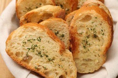 Tasty baguette with garlic and dill in basket, closeup