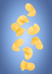 Raw horns pasta flying on blue background