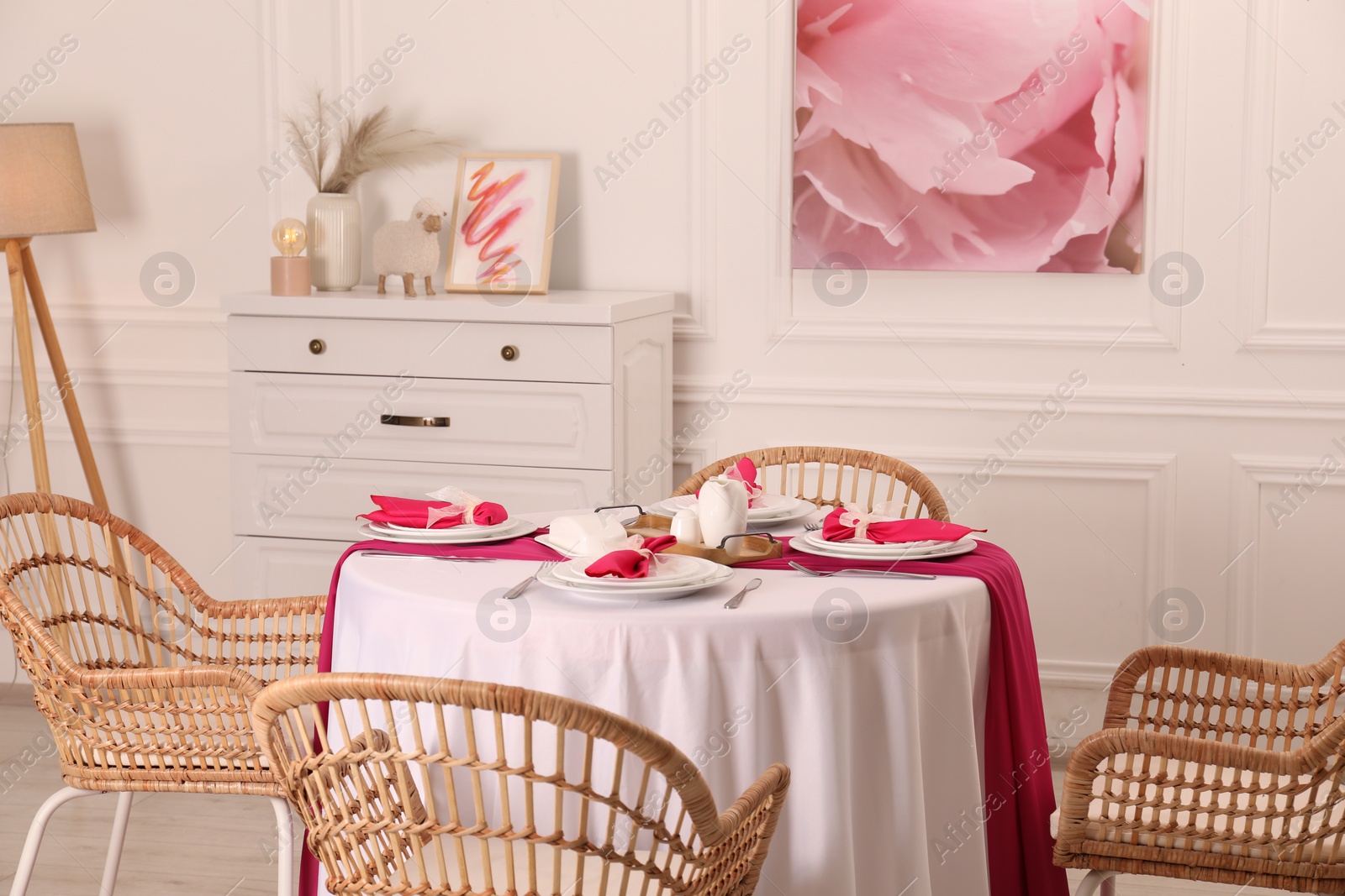 Photo of Color accent table setting. Plates, cutlery and pink napkins in dining room