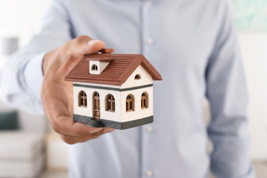 Real estate agent holding house model, closeup
