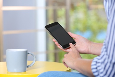 Photo of Woman holding smartphone with blank screen on blurred background. Mockup for design