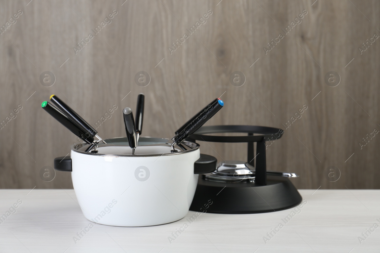 Photo of Fondue set on white wooden table, closeup