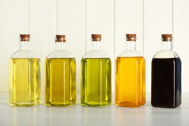 Vegetable fats. Different cooking oils in glass bottles on white wooden table