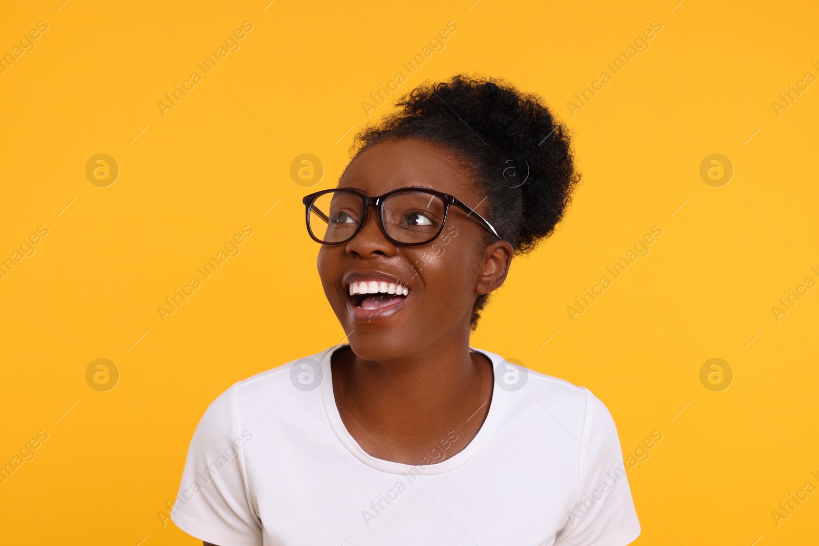 Photo of Portrait of happy young woman in eyeglasses on orange background