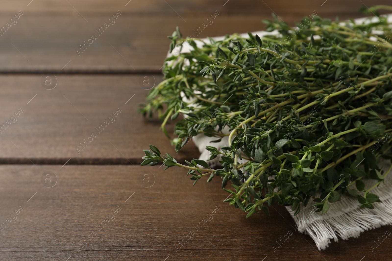 Photo of Bunch of aromatic thyme on wooden table, closeup. Space for text