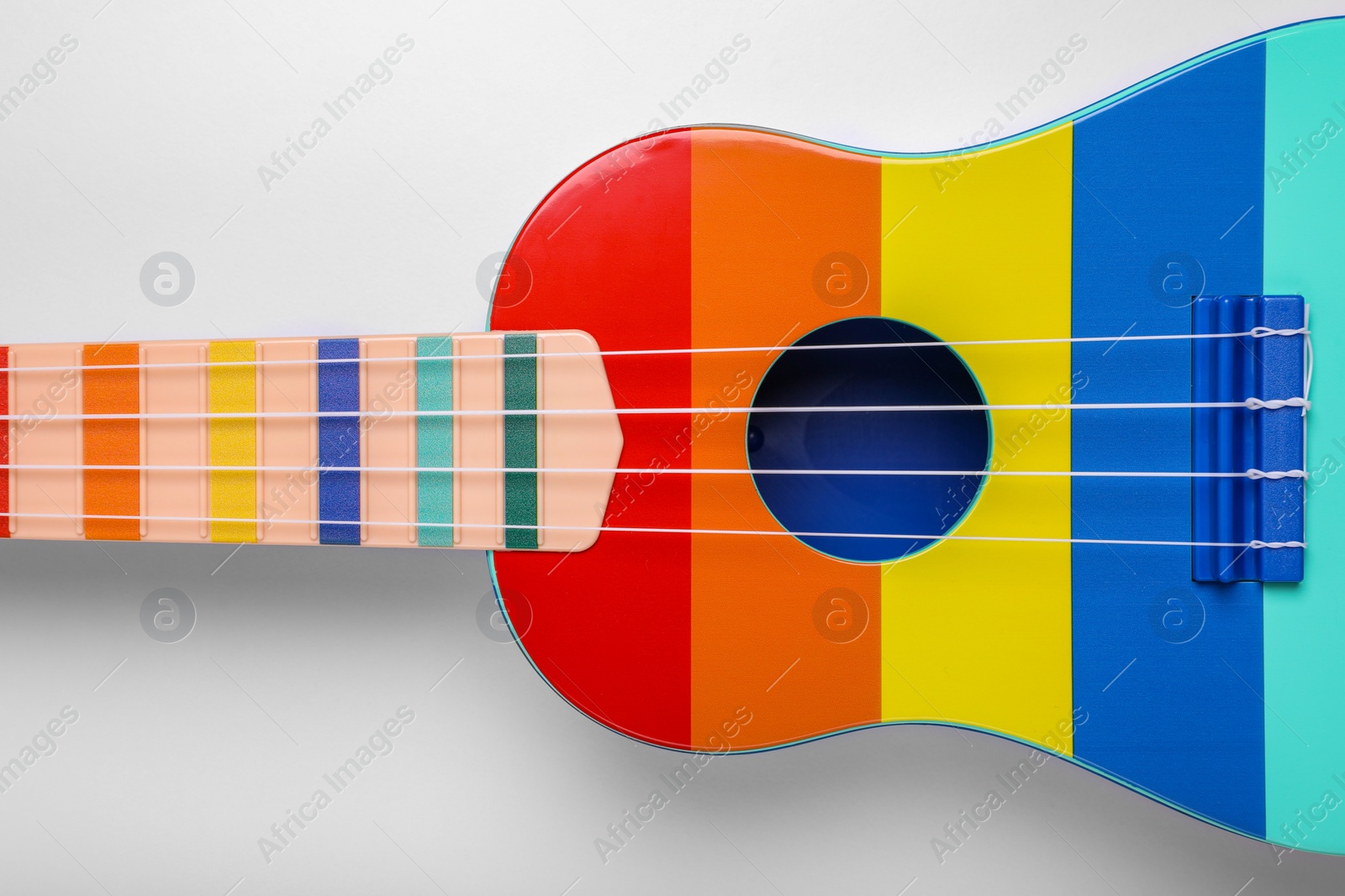Photo of Colorful ukulele on white background, top view. String musical instrument