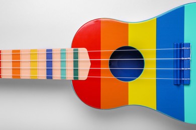 Photo of Colorful ukulele on white background, top view. String musical instrument