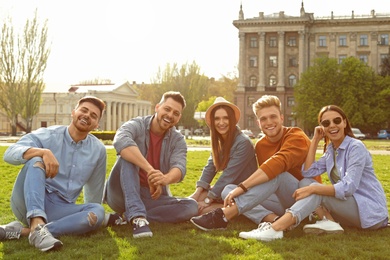 Happy people sitting on green grass in park