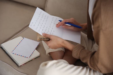 Photo of Woman writing letter while sitting on sofa at home, closeup