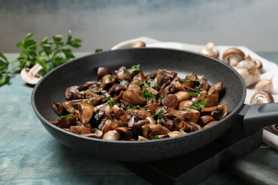 Frying pan with mushrooms on wooden table, closeup