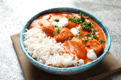 Bowl of butter chicken with rice on grey table