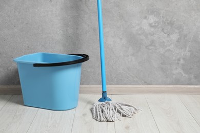 Photo of Mop and plastic bucket indoors. Space for text