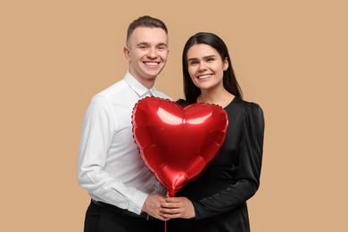 Lovely couple with heart shaped balloon on beige background. Valentine's day celebration