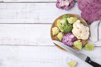 Photo of Various cauliflower cabbages on white wooden table, flat lay. Space for text